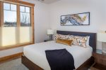The guest bedroom has a modern-rustic esthetic with a queen bed.